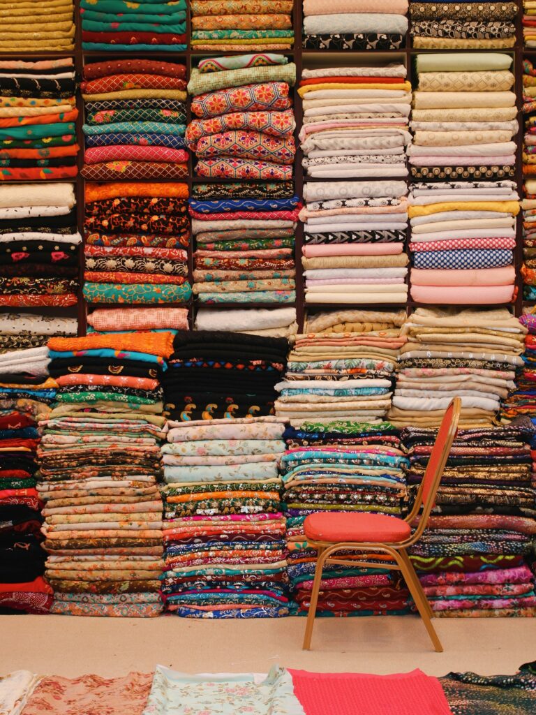 Stacks of colourful folded fabric on display in a textile shop, similar to those found on Arab Street
