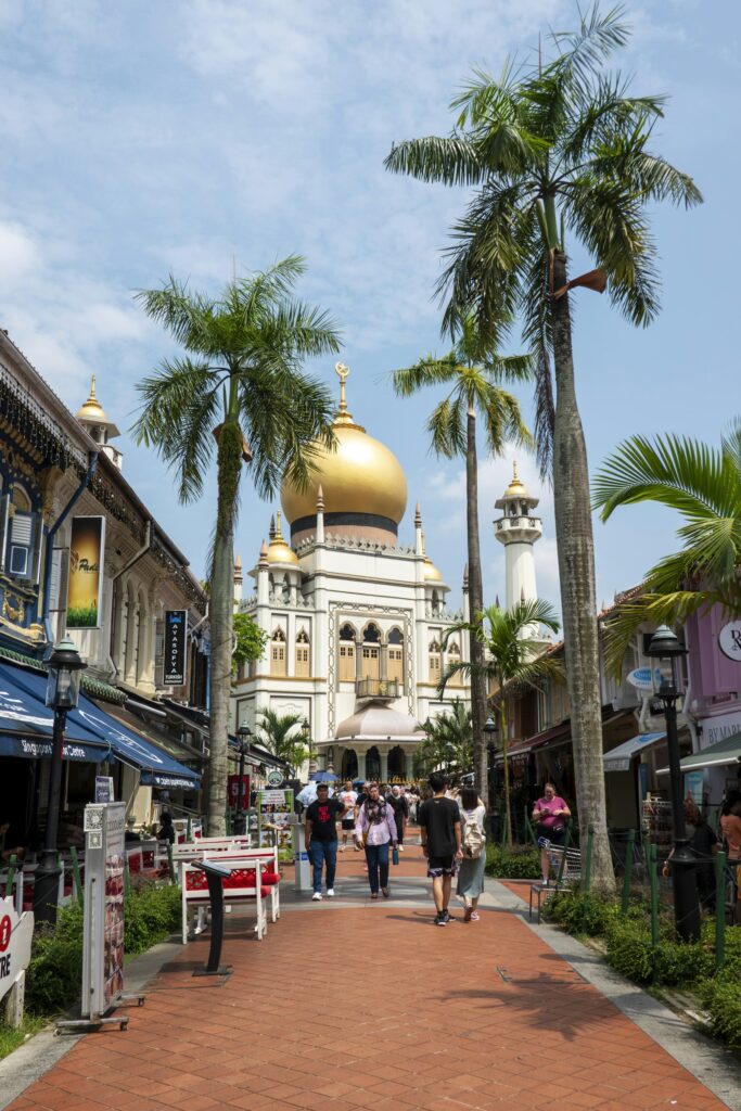 Outdoor dining tables along Bussorah Street in Kampong Glam with Sultan Mosque in the background