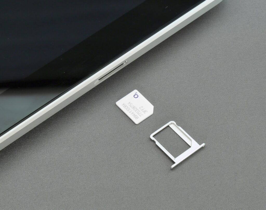 SIM card being inserted into a smartphone tray, representing staying connected while traveling in Singapore